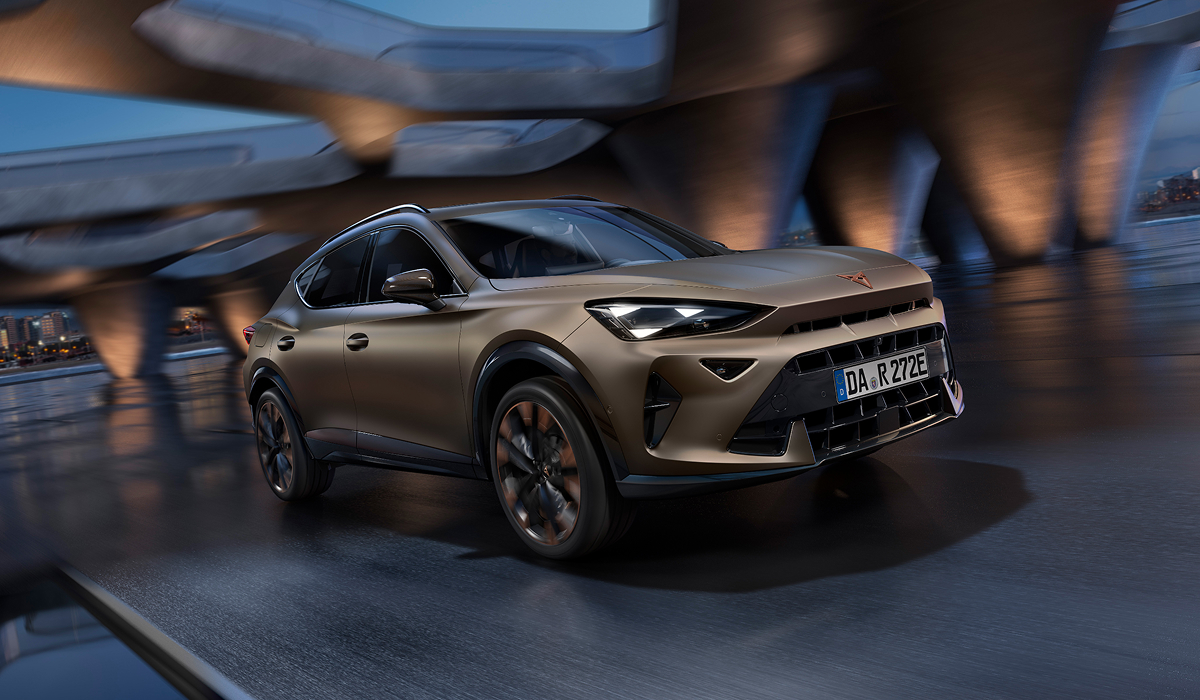 CUPRA Formentor e-HYBRID in mattem Bronze von schräg vorne fahrend vor moderner Architektur bei Nacht